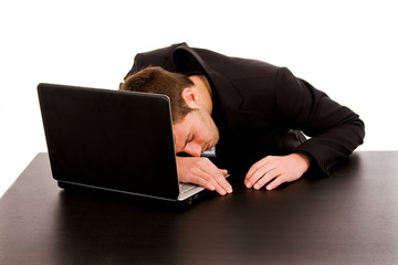 yawning young business man on the desk, isolated on white backgr