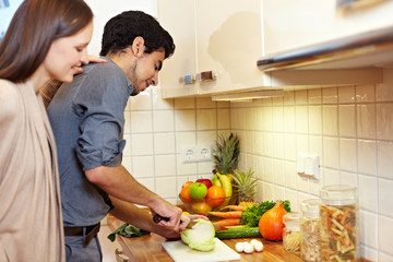 Frau schaut Mann beim Kochen zu
