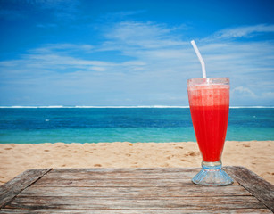 Freshly squeezed watermelon juice on a wooden table. Tropical background. Beach.