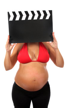 pregnant woman with beautiful belly holding movie clacket