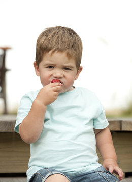 little boy enjoying eating a strawberry