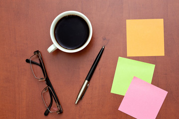 Reminder notes, pen and glasses with cup of coffee