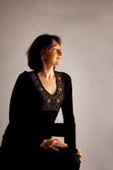 Mature woman in black sit in dark