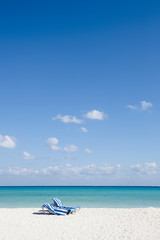 Fototapeta na wymiar Beach chairs on perfect tropical white sand beach
