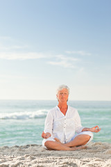 Fototapeta na wymiar Mature woman practicing yoga on the beach