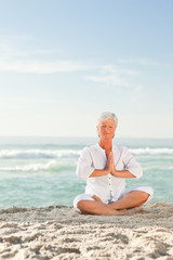 Fototapeta na wymiar Mature woman practicing yoga on the beach