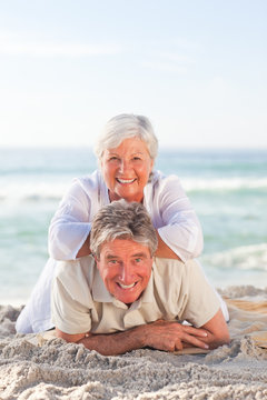 Elderly couple lying down on the beach