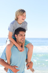 Fototapeta na wymiar Father having son a piggyback at the beach