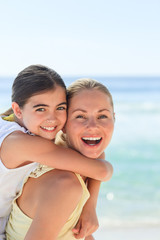 Fototapeta na wymiar Mother having daughter a piggyback at the beach