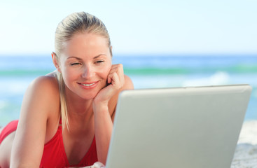 Lovely woman working on her laptop at the beach