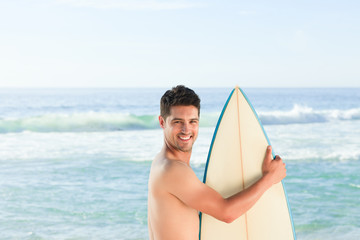 Handsome man beside the sea with his surfboard