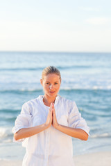 Active woman practicing yoga on the beach