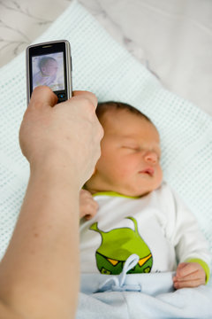 Mother taking photo of her newborn child by mobile phone