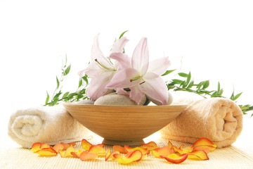 A spa composition of stones, pink flowers and two towels