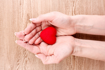 red heart in hands on wooden background
