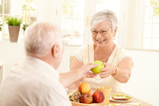 Laughing senior wife getting apple from husband