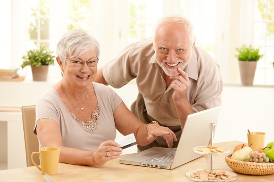 Portrait of happy old couple shopping online