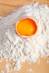 Flour with raw eggs for making dough on wooden background
