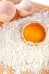 Flour with raw eggs for making dough on wooden background