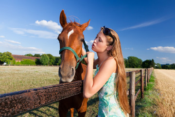 Fototapeta premium horse and blond girl in paddock on summers