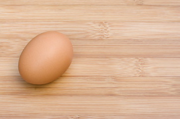 Single egg on wooden table, view from top, space for text