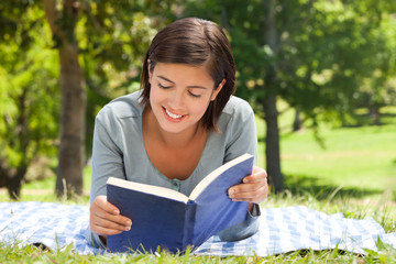 Fototapeta premium Woman reading a book in the park