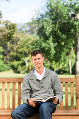 Fototapeta premium Young man reading his book on the bench
