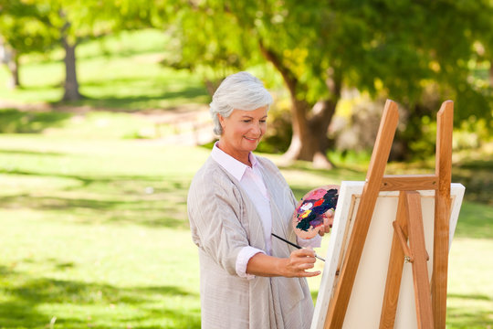 Senior woman painting in the park