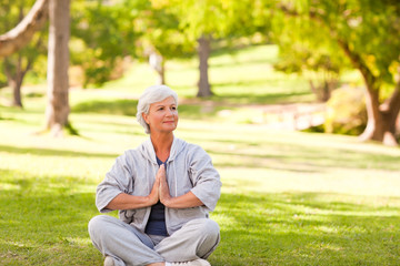 Fototapeta premium Mature woman practicing yoga in the park