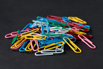 Colorful paper clips on black paper background