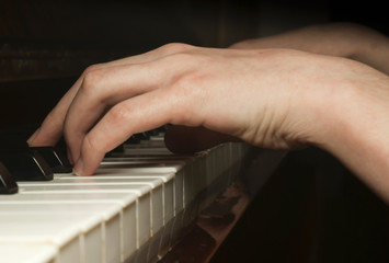 Child's hand playing on piano keyboard