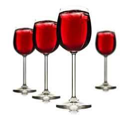 Four wine glasses with red fruit juice and ice
