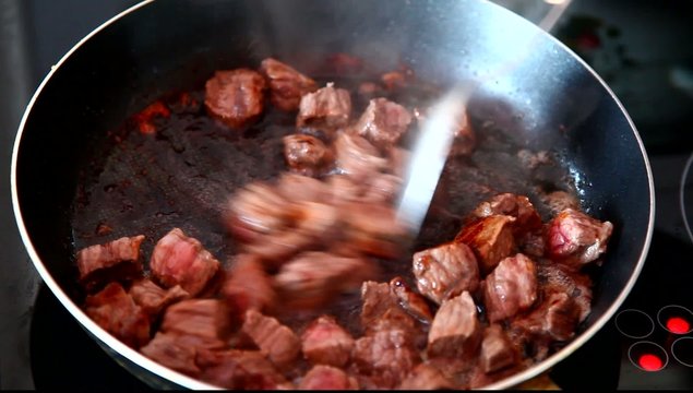 Chef frying meat in a pan