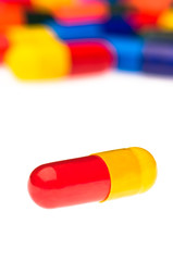 One red yellow capsule in front of many colorful