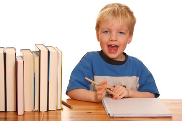 Kleiner Junge mit Stiften am Schreibtisch