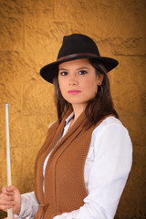 Portrait of a young suggestive brunette with hat and pool stick