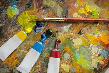 Art tools. Multicolored artist's palette with spots of paint, brush and tubes of paint