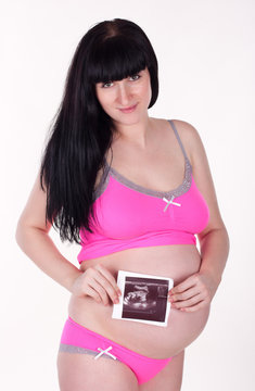 A shot of a pregnant woman carrying her child's ultrasound pictu