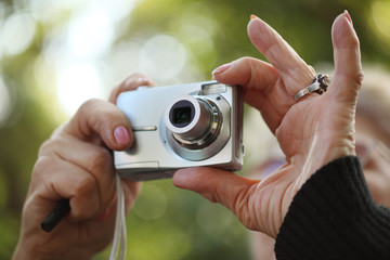 Senior woman hands holding compact photo camera