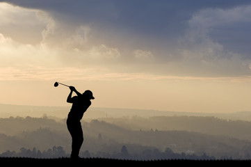 Golfer silhouette against stunning sunset sky