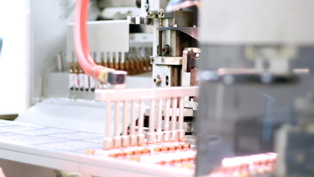 Robotic Arm - Ampoule Packaging Line. Pharmaceutical Industry Robotic Arm Packaging Ampoules On The Production Line. Vaccine Manufacturing. Pharmaceutical Production.