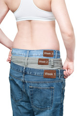 Yuong woman monitoring weight loss by wearing tree jeans.