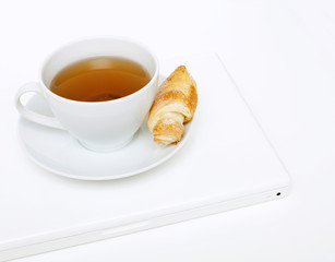 cup of tea, croissant and laptop