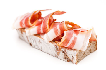 Ein mit Speck belegtes Brot auf weißem Hintergrund