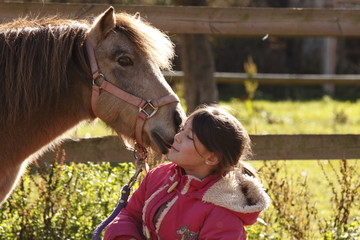 enfant avec un  poney lui faisant un bisou