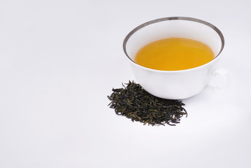 white cup of hot green tea with tea leaves on white background