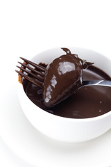 melted chocolate in a cup, fork and strawberries isolated on whi