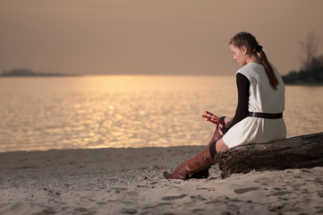 Lonely woman sitting on lake coast