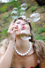 The beautiful woman starts up soap bubbles