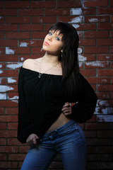 fashion portrait of young woman with a brick wall